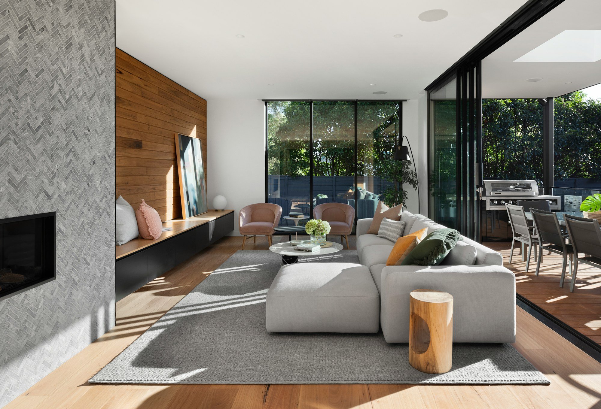 Interior livingroom with cedar plank walls and modern grey sofa surrounded by floor to ceiling windows.